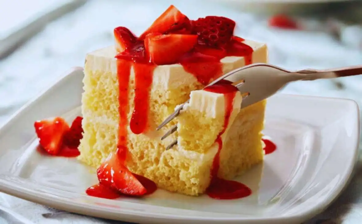 Olive Garden strawberry cream cake topped with fresh strawberries and sweet strawberry sauce